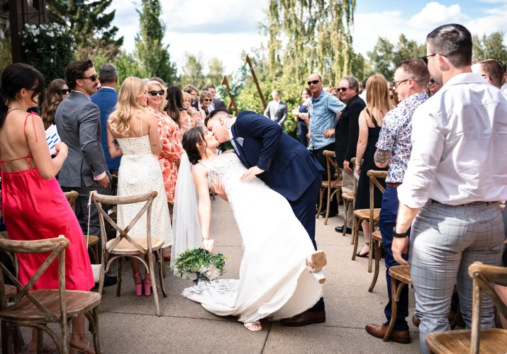 bride and groom walking down the aisle and share a kiss at the Calgary Wedding Ceremony.