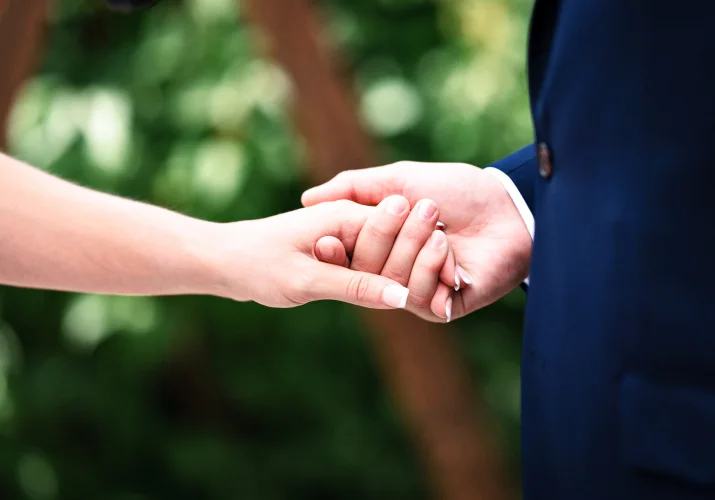 Groom holds the bride's hand.