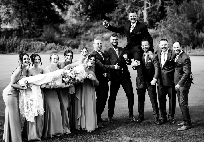 Funny photography of the bridal party lifting up the bride and groom.