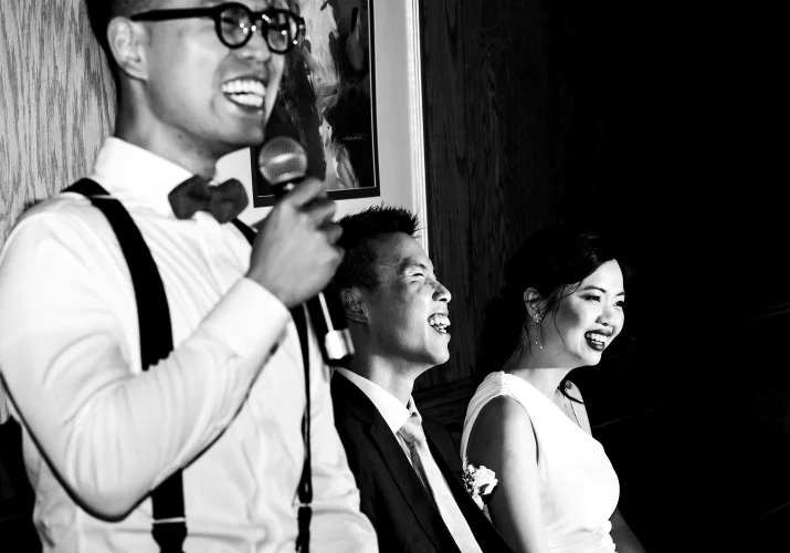 photograph of the batsman giving a speech. Newlyweds laugh. Moment captured by Banff Wedding Photographers.
