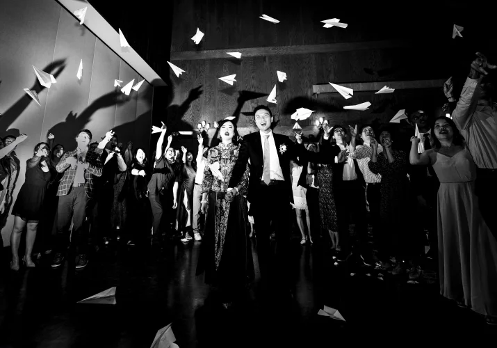 bride and groom walk while the quests through the paper planes. Creative photograph taken by Banff Wedding Photograph.