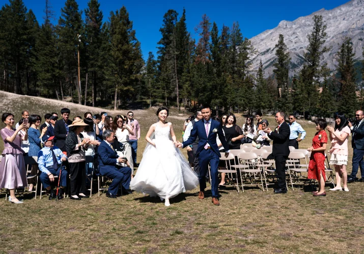 newlyweds run back on the aisle while all banff quests clapping their hands