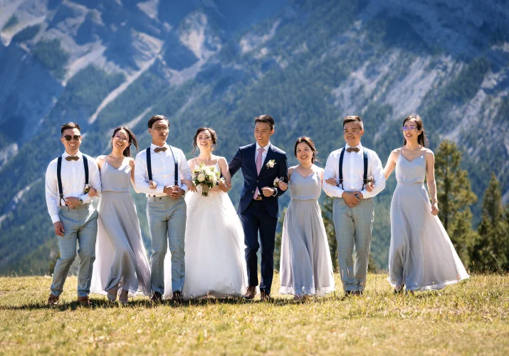 Wedding Party walk with linked arms and have fun at Tunnel Mountain in Banff.