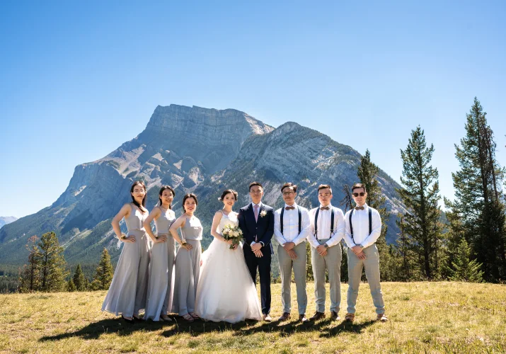 Wedding Party Banff Photograph while they look at the camera. Behind them stunning Rocky Mountains.