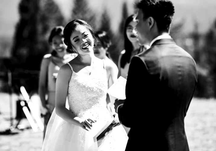 Bride smiles to the groom while he gives a speach during banff wedding ceremony.