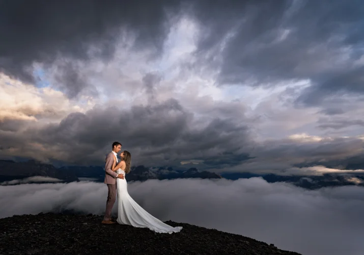 Newlyweds in a hug, facing each other at the top of the mountain in the Canadian Rockies.
