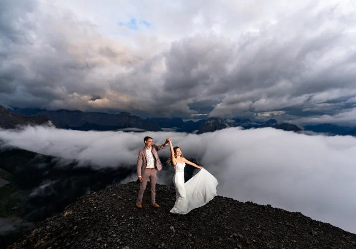 Newlyweds first dance at the top of the mountain during elopement. Moment captured by Banff Wedding Photographer in a cloudy day.