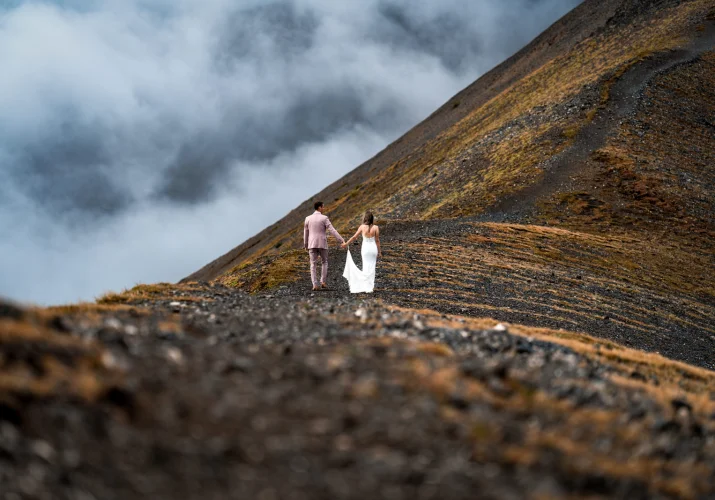 Bride and groom hold their hands and walk at the mountain ridge in the Canadian Rockies.