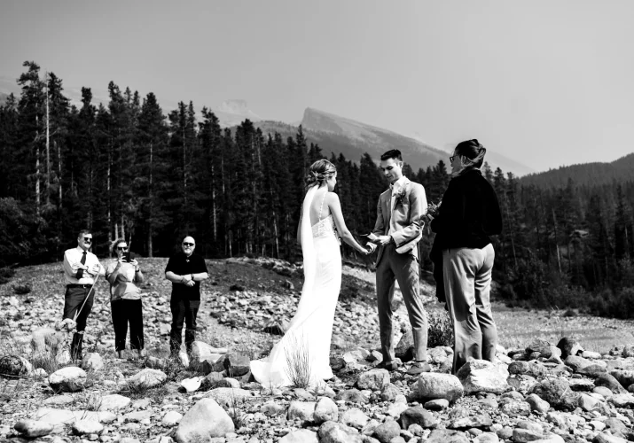 Elopement ceremony in Banff captured by Banff Wedding Photographer. Bride and groom hold their hands and family stand behind.