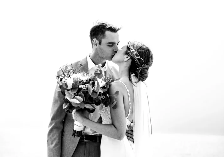 A newlywed couple shares a romantic kiss against the backdrop of the lake in Banff.