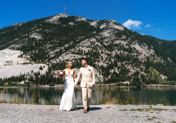 Bride and groom walk and hold their hands in the mountains.