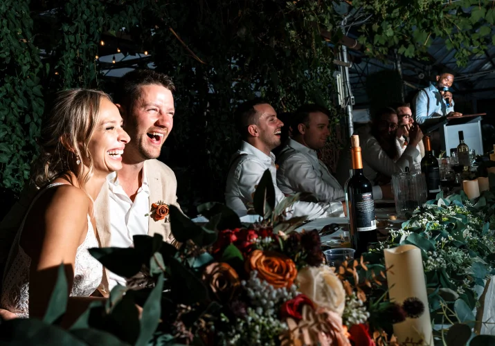 Gride nad groom laugh a lot while best men gives a speech.