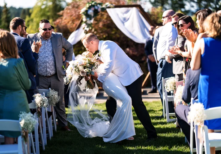 Bride and groom share a kiss while walking back the aisle during Calgary Wedding