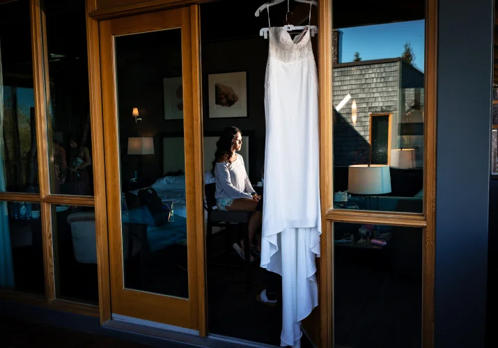 Calgary Wedding Photography of the wedding dress hanging at the widow and the bride having make up done