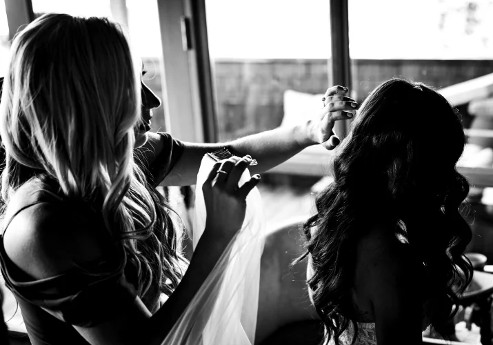 Canadian wedding photography of the hairdresser putting veil on the bride