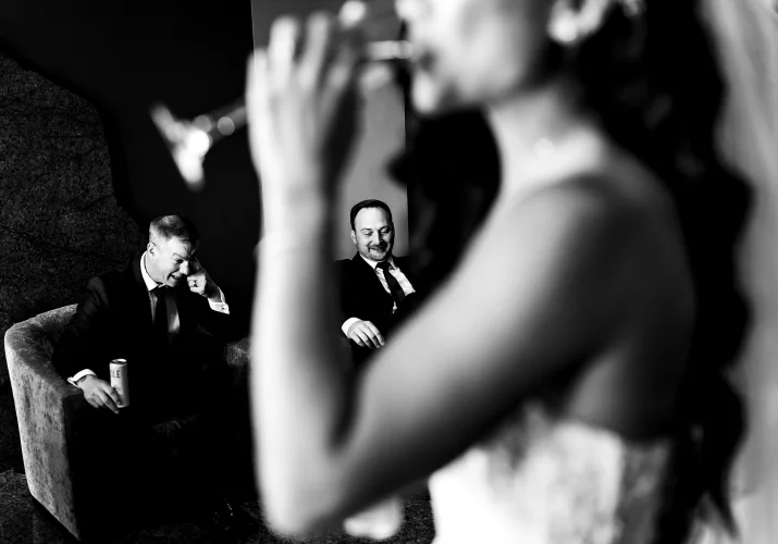 shoot through of wedding guests in Calgary looking at the drinking bride