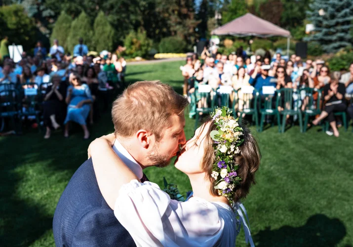 First kiss at the wedding in Calgary Zoo. Behind all the guests watching bride and groom.