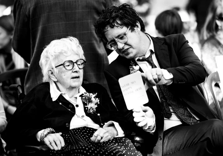 A man shows the grandmother the schedule of the Calgary Wedding