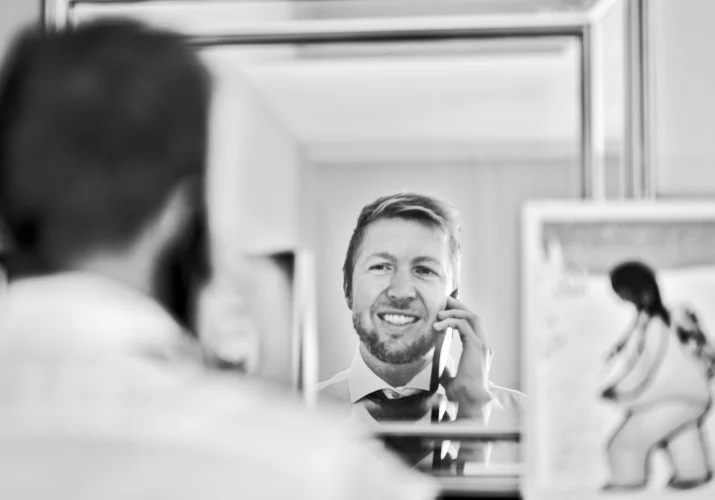 Groom looks at the mirror and talks with the bride before Calgary Wedding.