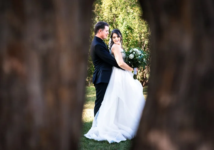 Bride and groom in a hug between trees