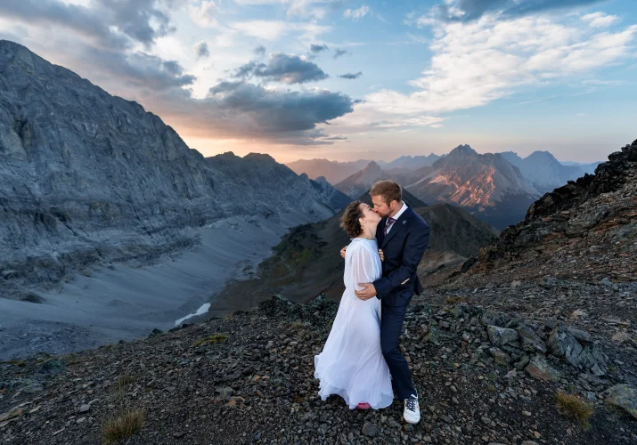 a first kiss of the newlyweds at Pocatera Ridge duting Banff Wedding Adventure