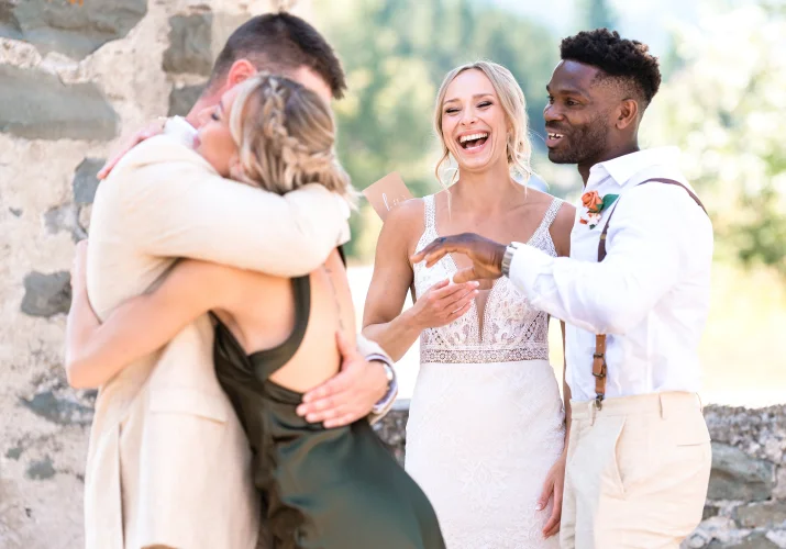 groom hug his sisster while the bride and best men siles.