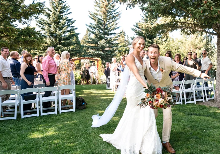 Bride and groom run down the aisle and scream into the camera. Quests are watching.