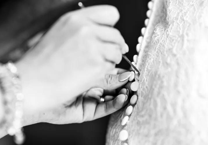 Black and white photograph od the hands zipping the wedding dress.