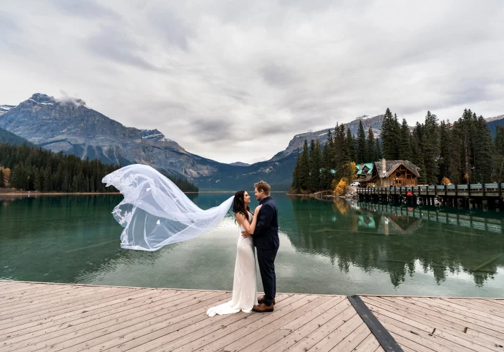 Bride and groom facing each other while the veil flying on the wind.