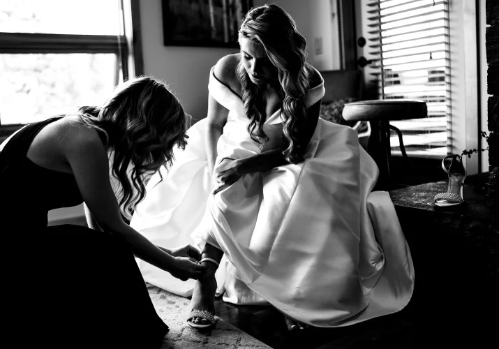 Bridesmaid put the wedding shoe on the brides leg before elopement in Banff.