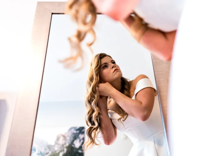 Banff wedding photography of the bride putting her earrings on in front of the mirror.