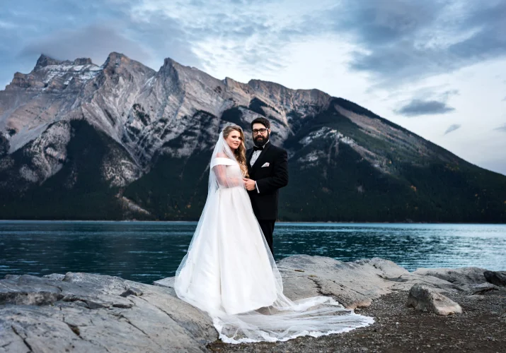 Banff Elopement Portrait at Minnewanka Lake with the bride and groom looking at the camera.