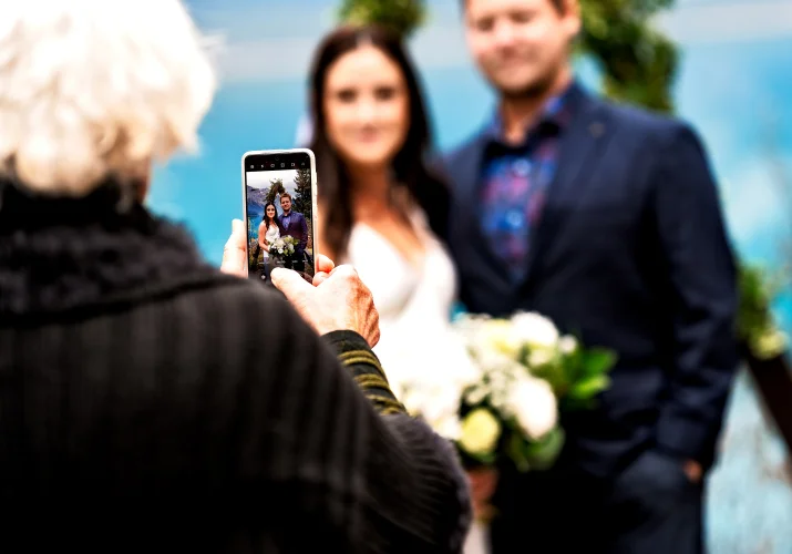 Mather of the bride takes a photo of the bride and groom at the wedding