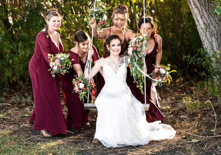 Bridal party swing the bride on the swing. They are having fun an the wedding day in Calgary.