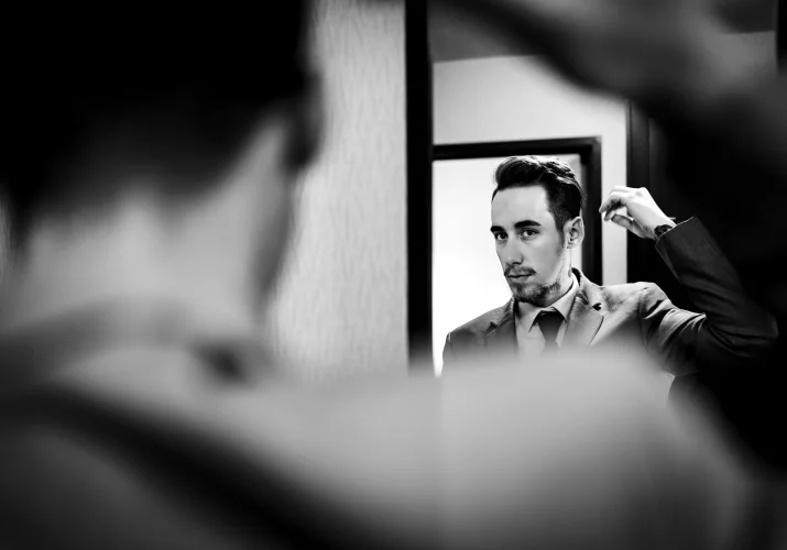 The groom brushes his hair in front of the mirror.