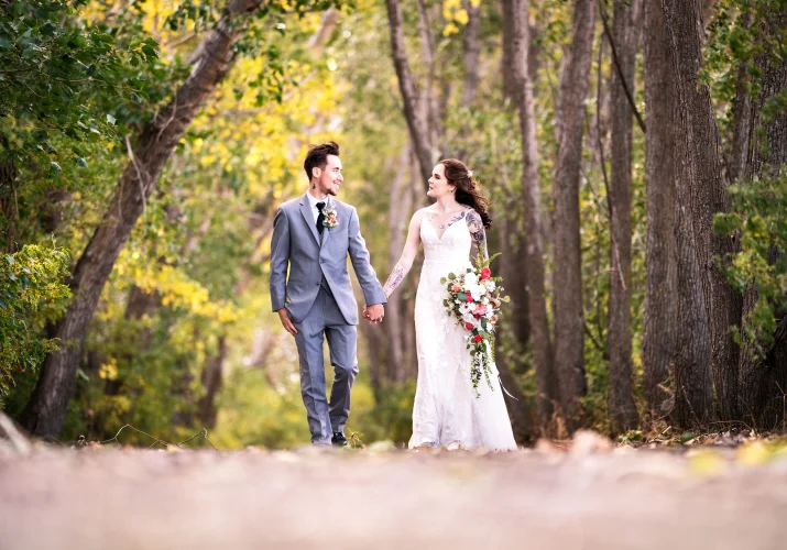 Calgary Wedding Photograph of the bride and groom walkin in the forest
