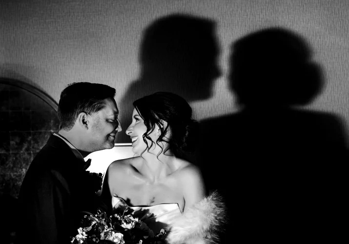 Bride and groom look at each other with their shadow on tthe wall