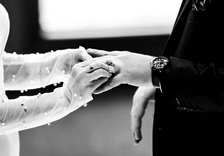 hands of the newlyweds exchanging wedding rings