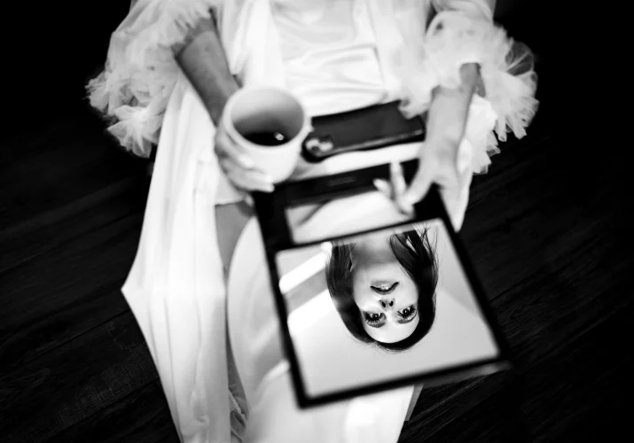 Camore wedding photography of the bride sitting on the chair with her face reflected in the small mirror