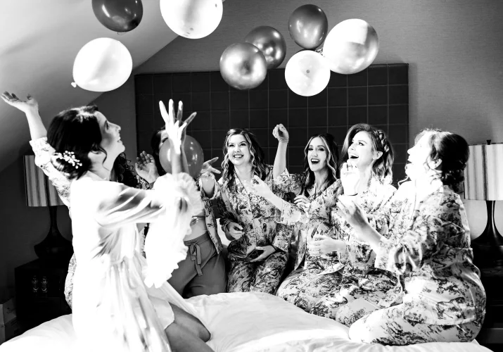 wedding party plays with the balloons on the bed in pyjamas