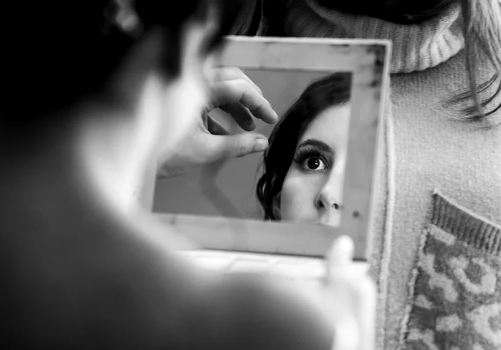 Brides reflection in the mirror while she fixes her hair.