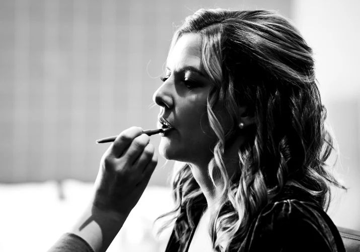make up artists hand put a lipstick on the bride's lips