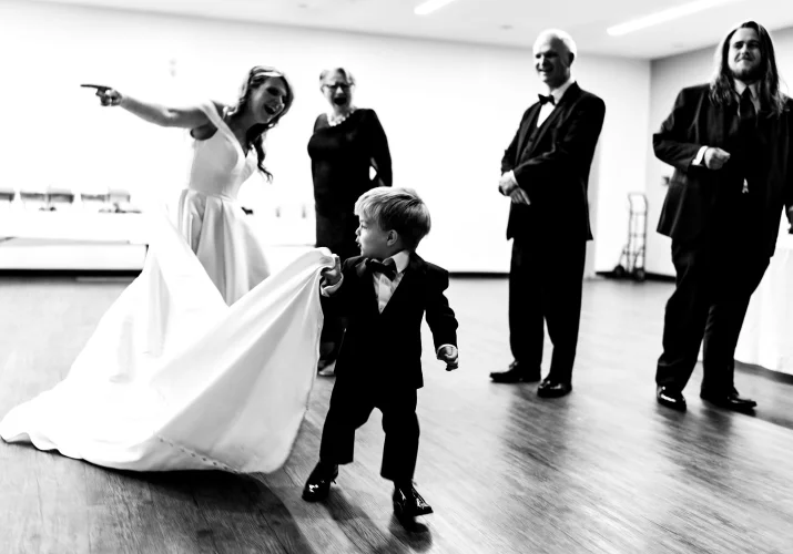 Son of the bride pulling her wedding dress.