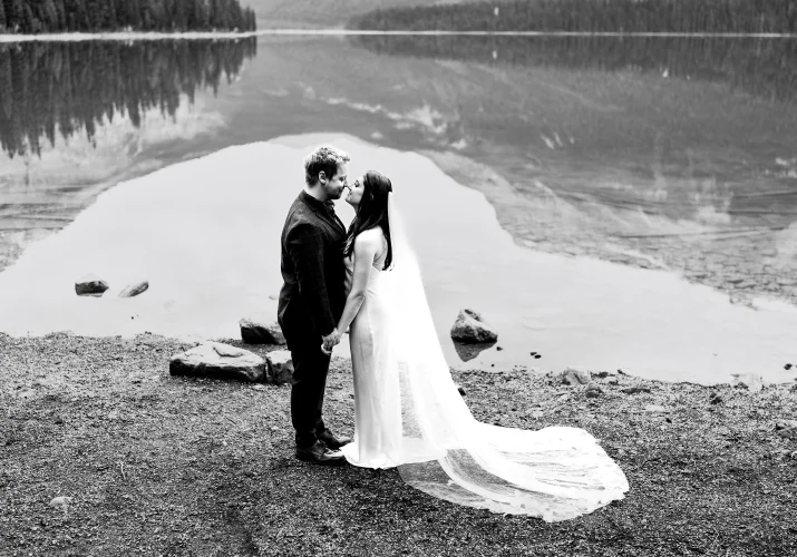 Black and white wedding portrait of the bride and groom facing each other by the Emerald Lake