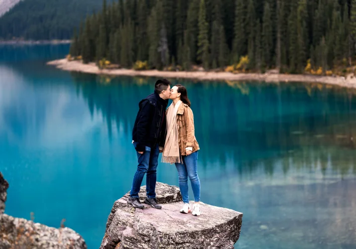 Couple in love share a kiss at the turquoise Moraine Lake.