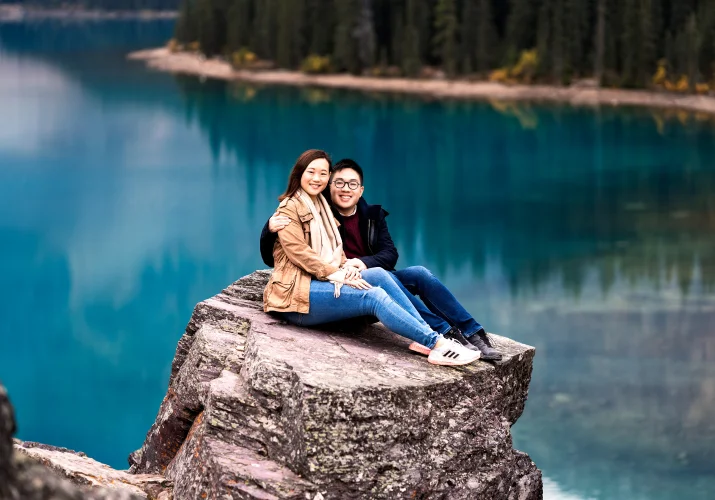Engaged couple sits at the huge rock at Moraine Lake