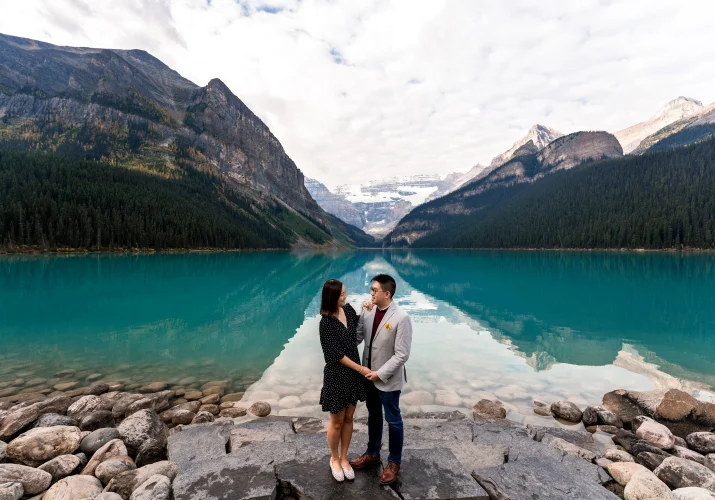 Banff Engagement Photography of couple in love holding hands at turquoise Lake Louise