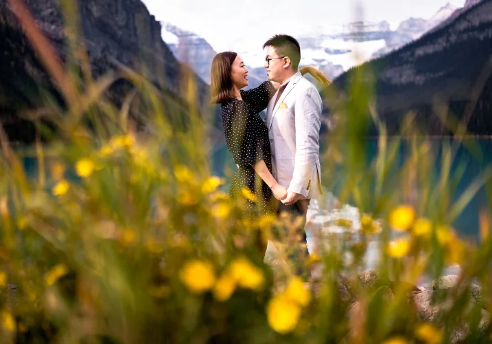 Young couple in love look at each other surrounded by yellow flowers.