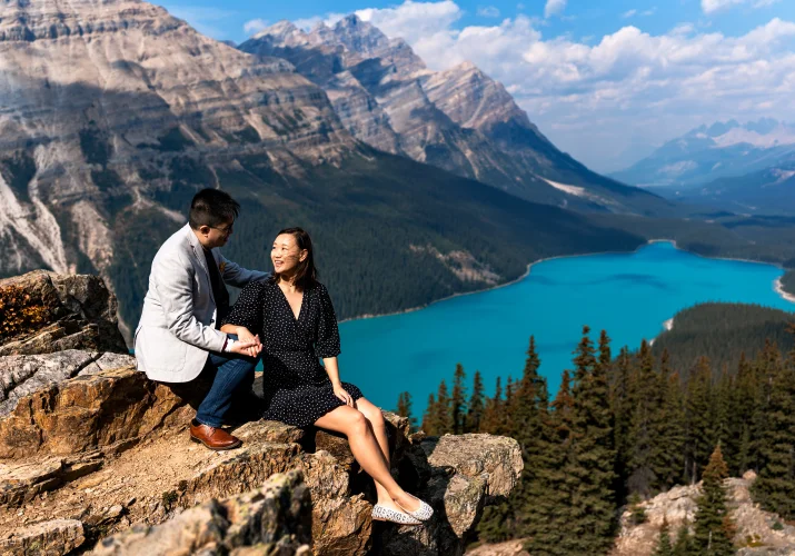 Peyto Lake Engagement Photography of the couple sit at the cliff overlooking stunning blue lake in Banff National Park