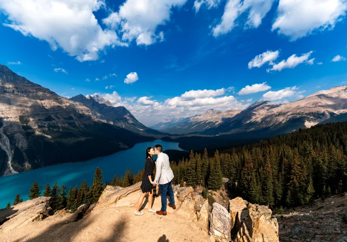 Engaged couple share a kiss at Peyto Lake in the mountains